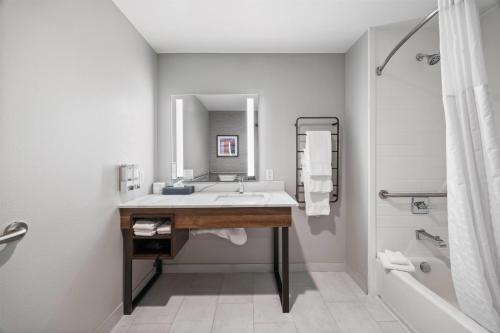 a bathroom with a sink and a mirror and a tub at La Quinta Inn & Suites by Wyndham La Habra in La Habra