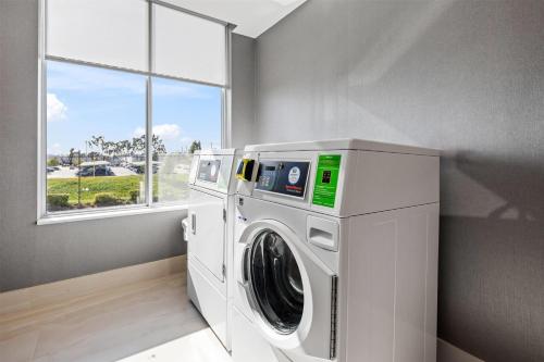 a washing machine in a laundry room with a window at La Quinta Inn & Suites by Wyndham La Habra in La Habra