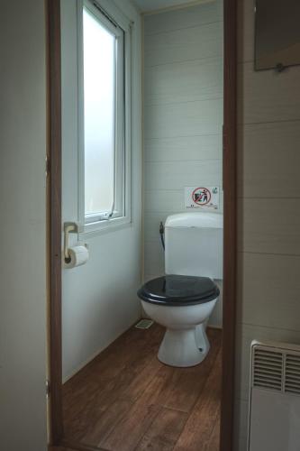 a bathroom with a toilet with a black seat at Camping Playa Arenillas in Islares