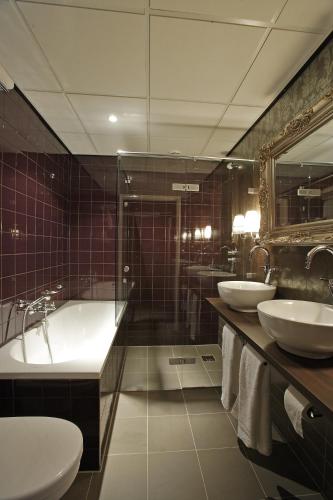 a bathroom with two sinks and a tub and a shower at Hotel Mijdrecht Marickenland in Mijdrecht