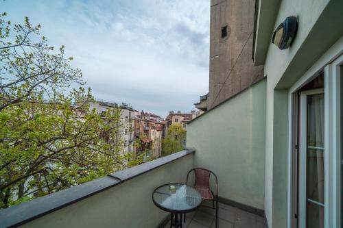 a balcony with a table and chairs and a window at Hotel Raffaello Prague in Prague