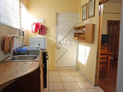 a small kitchen with a sink and a door at Grazia Cottages in Port Nolloth