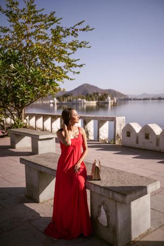 a woman in a red dress sitting on a bench at Panna Vilas - A Lake Facing Boutique Hotel in Udaipur