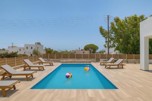 une piscine avec des ballons de volley et des ballons de volley sur une terrasse dans l'établissement Ippocampos Seaside Serenity - Unwind at Paros Poolside Retreats, à Aliki