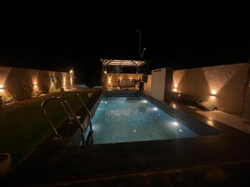 a swimming pool at night with lights on it at Aaroha Cove in Kālwāra
