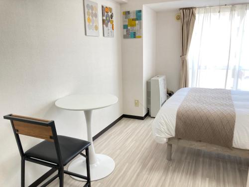 a bedroom with a bed and a table and a chair at Endless Mitsui Minami 5jo II in Sapporo