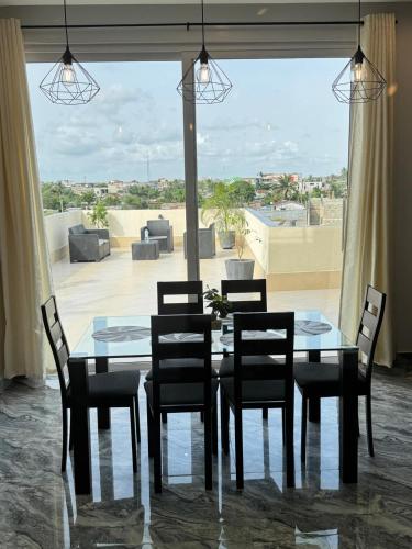 a dining room table and chairs with a view of a patio at RESIDENCE MH SERVICES Cotonou in Cotonou
