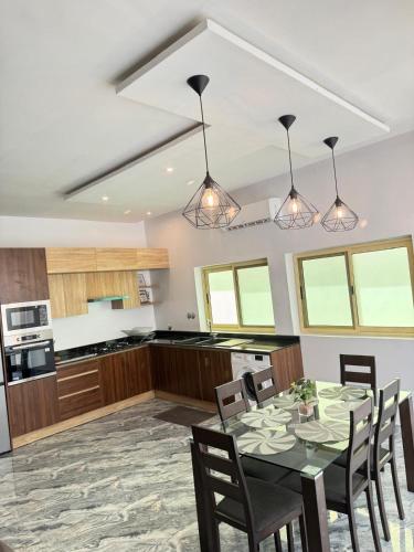 a kitchen with a table with chairs and lights at RESIDENCE MH SERVICES Cotonou in Cotonou