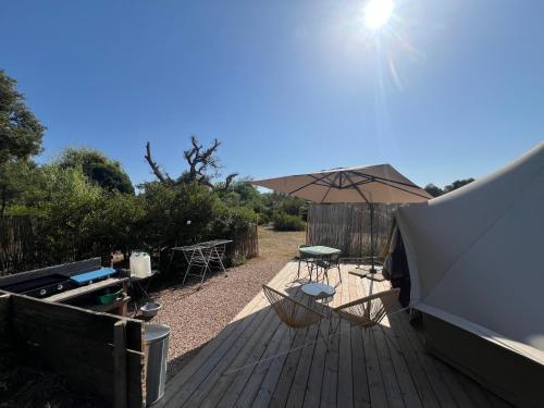 a deck with an umbrella and a table and chairs at Le Tipi in Lecci