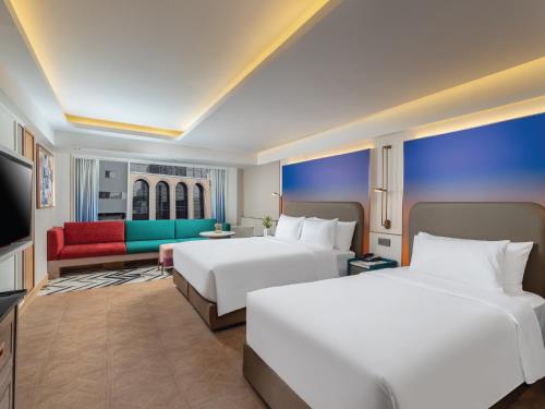 a hotel room with two beds and a couch at Pipa Hotel Bangkok Sukhumvit 11 in Bangkok