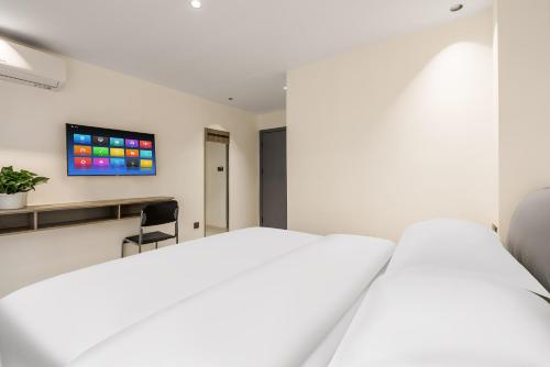 a bedroom with two beds and a tv on the wall at SX hotel in Chengdu