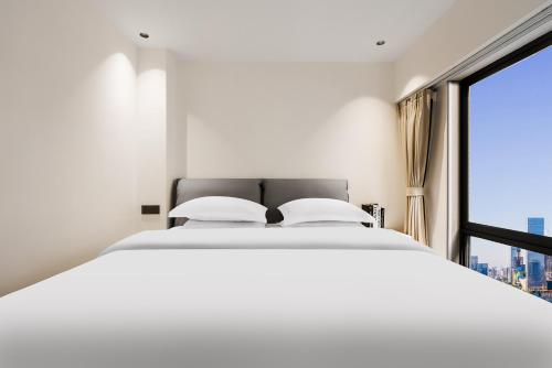 a bedroom with a white bed and a large window at SX hotel in Chengdu