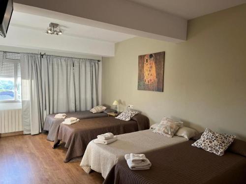 a hotel room with three beds and a window at Pensión Plaza in Palas de Rei 
