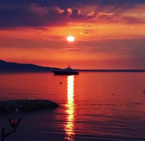 un bateau dans l'eau avec un coucher de soleil dans l'établissement Atelier Sonia, à Roquebrune-Cap-Martin