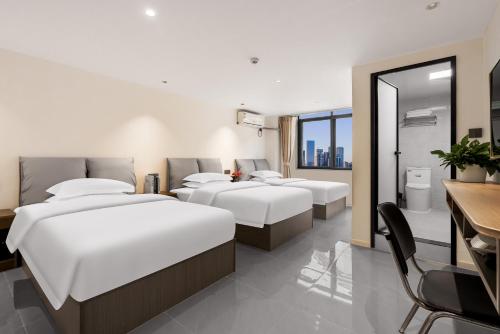 a hotel room with four beds and a table and a desk at SX hotel in Chengdu