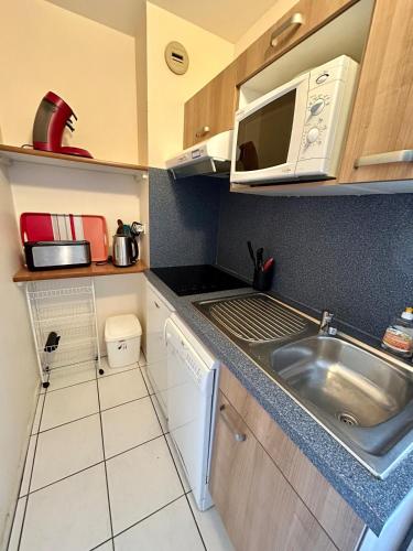 une petite cuisine avec un évier et un micro-ondes dans l'établissement T2 nature avec terrasse cosy, à Bénodet