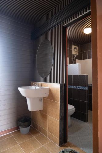 a bathroom with a sink and a mirror and a toilet at JHP Apartment in Udon Thani