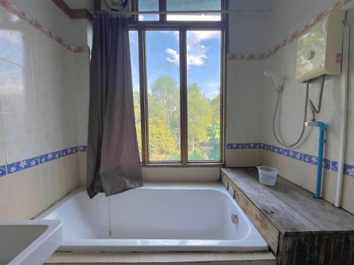 a bath tub in a bathroom with a window at Muangkham in Chiang Rai
