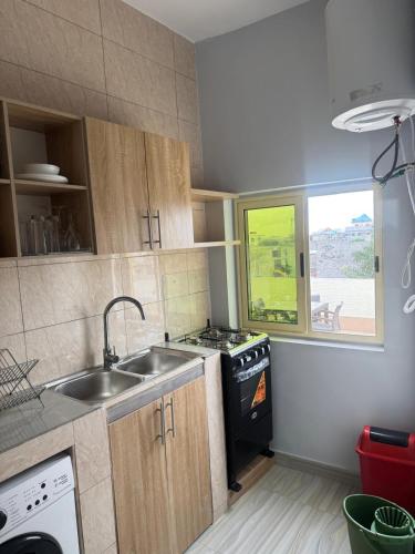 a kitchen with a sink and a stove and a window at RESIDENCE MH SERVICES Cotonou in Cotonou