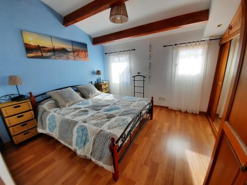 - une chambre avec un lit, des murs bleus et du parquet dans l'établissement La maison de la mer, classée 3 étoiles, à Frontignan