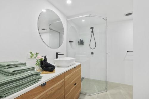 a bathroom with a sink and a shower with a mirror at Two bedroom river view unit with pool in Maroochydore