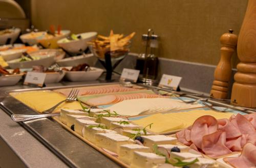 a buffet with cheese and meats on a table at Lion's Garden Hotel in Budapest