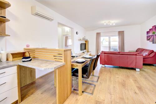 a kitchen and living room with a table and a red couch at Cool Šilo Appartement Resort in Šilo