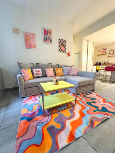 a living room with a couch and a table on a rug at Lyon funky flat piscine et parking in Tassin-la-Demi-Lune