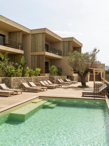un complexe avec une piscine, des chaises et un bâtiment dans l'établissement Résidence Oradoro - Nouvel établissement, à Belgodère