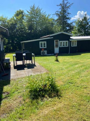 a house with a table and chairs in a yard at A Cozy Older Summerhouse On A Small Island in Orø