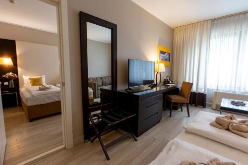 a room with a desk with a mirror and a bedroom at Lion's Garden Hotel in Budapest