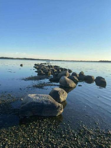 a group of rocks on a beach in the water at A Cozy Older Summerhouse On A Small Island in Orø