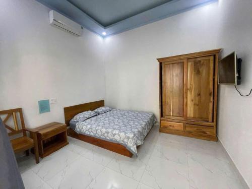 een slaapkamer met een bed en een houten kast bij Phu Quoc Green Bungalow in Phu Quoc