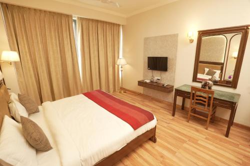 a hotel room with a bed and a desk and a mirror at Hotel Surya Residency, Amritsar in Amritsar