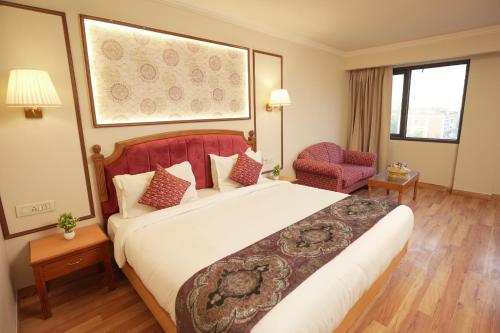 a hotel room with a large bed and a chair at Hotel Surya Residency, Amritsar in Amritsar