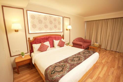 a hotel room with a large bed and a chair at Hotel Surya Residency, Amritsar in Amritsar