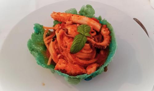 a plate of food with pasta and a garnishment at Hotel Colonne in San Giovanni Rotondo