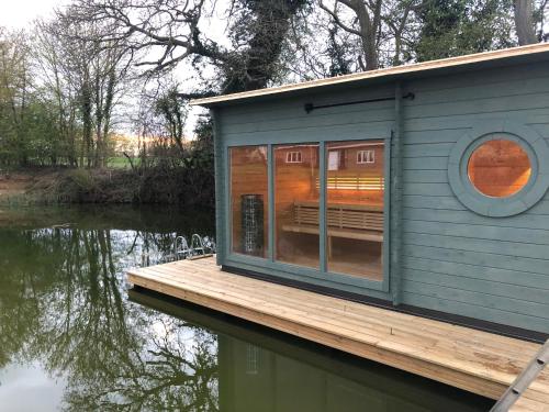 a tiny house on a dock on a body of water at Cherry Trees in Stowmarket