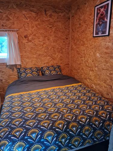 a bedroom with a bed with a blue and yellow comforter at La Chalan d'hier in Nort-sur-Erdre