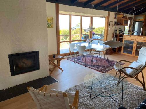 a living room with a fireplace and a table and chairs at Veddinge Odsherreddenmark - House With Seaview in Asnæs