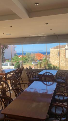a restaurant with tables and chairs and a view of the ocean at Loutra Beach Hotel in Agia Paraskevi