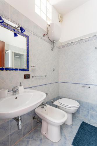 a white bathroom with a sink and a toilet at Carmine 21 in Bosa