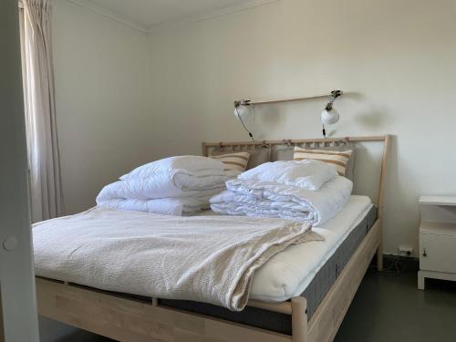 a bed with white blankets and pillows on it at Blokkhus historisk overnatting i Stavern in Larvik