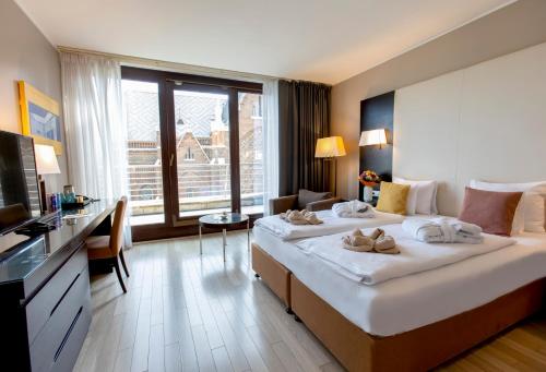 a hotel room with two beds and a television at Lion's Garden Hotel in Budapest