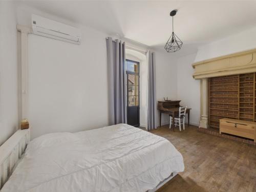 ein weißes Schlafzimmer mit einem Bett und einem Schreibtisch in der Unterkunft Maison pour 5 avec cour extérieure dans le centre in Saint-Léon-sur-Vézère