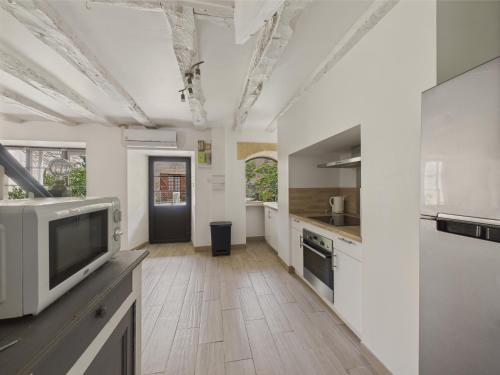 une grande cuisine avec des placards blancs et une télévision dans l'établissement Maison pour 5 avec cour extérieure dans le centre, à Saint-Léon-sur-Vézère