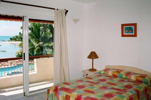 1 dormitorio con cama y vistas al océano en Villas Banyan, en Grand Gaube