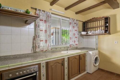 a kitchen with a sink and a washing machine at Casa Rural Cantarrana in Arriate