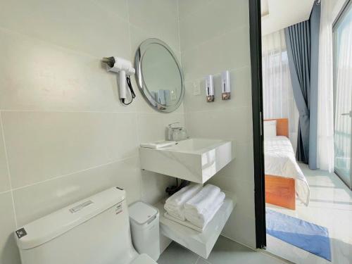 a bathroom with a sink and a toilet and a mirror at Blue Star Viên Hotel in Binh Tien