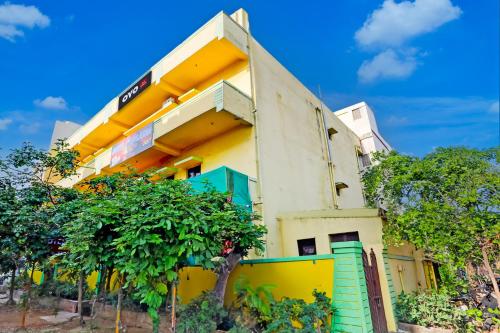 a yellow building with a tree in front of it at Hotel O Abhilasha in Bhilai
